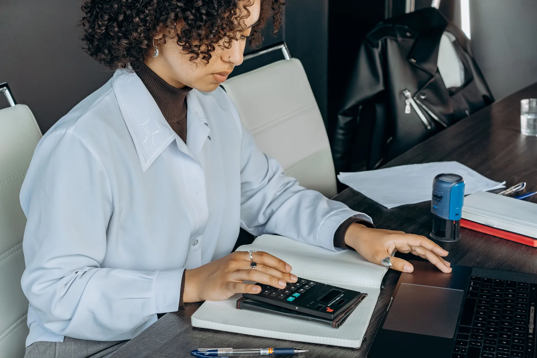 Professional accountant using a calculator and laptop