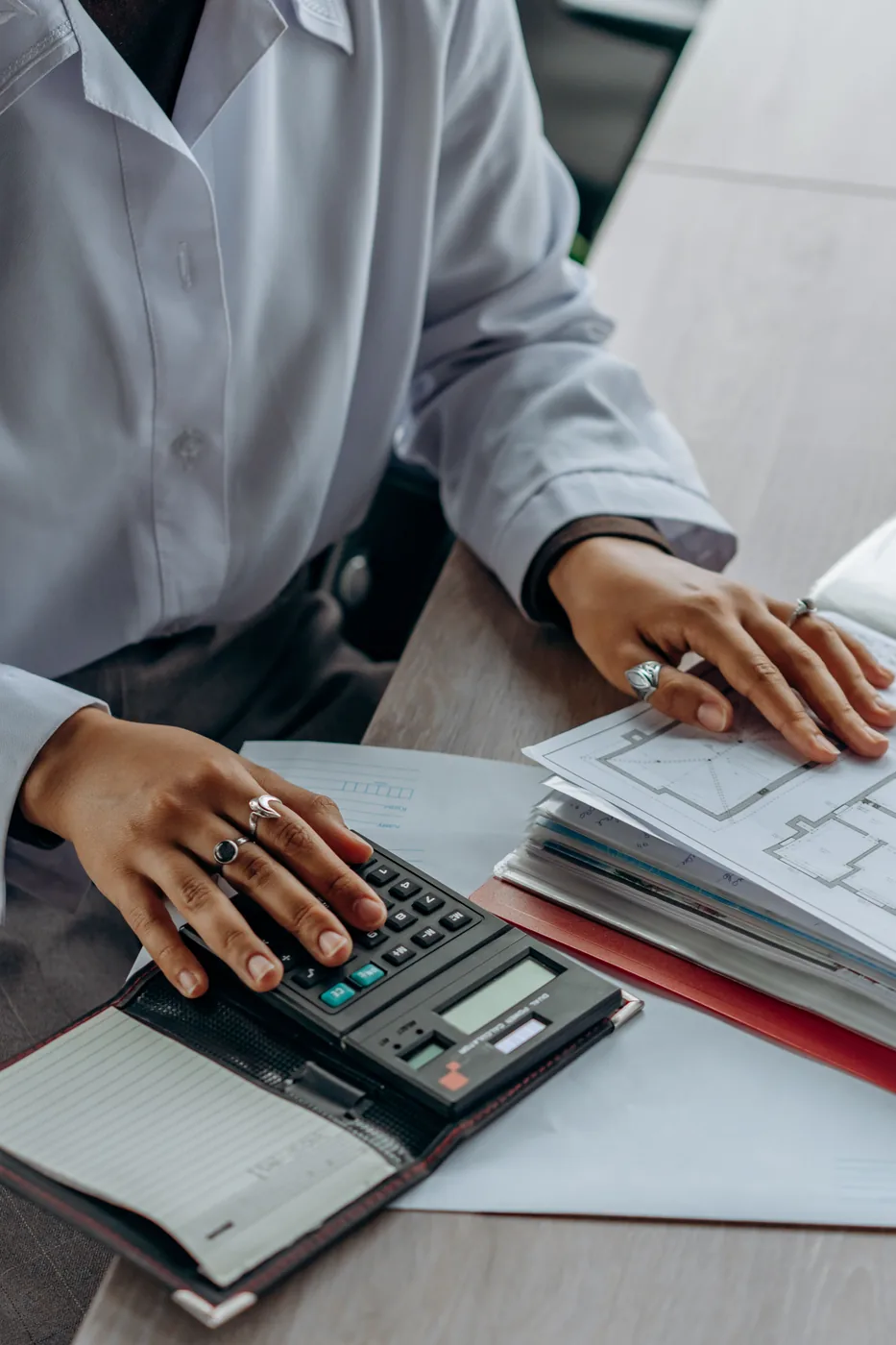 Professional reviewing documents with calculator for accounting work